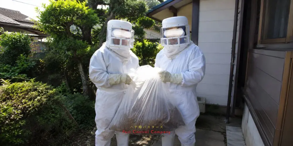 武蔵村山市で大きな蜂の巣を袋に入れて回収する作業員