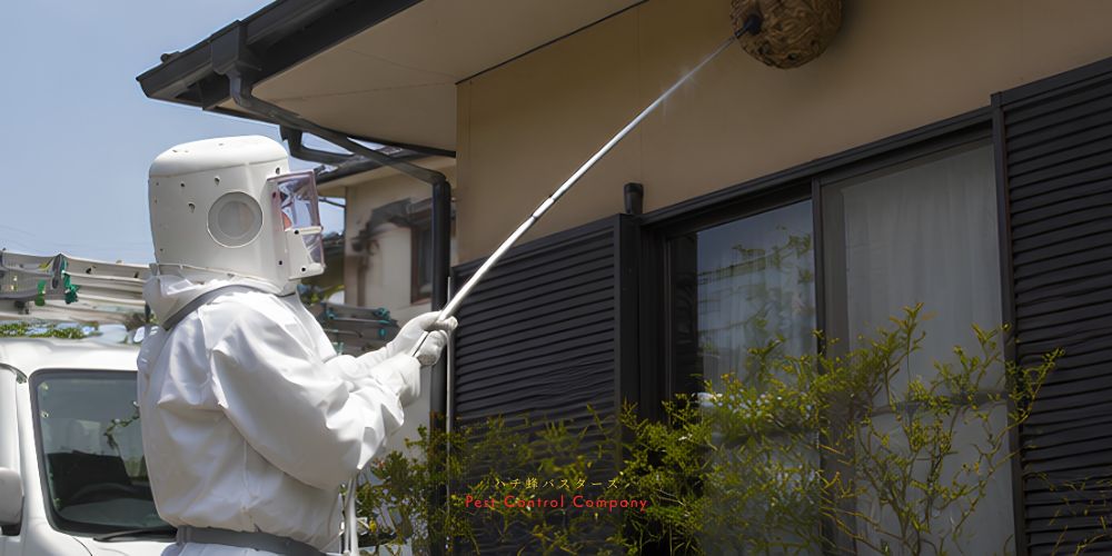 東京の住宅軒下にできたスズメバチの巣を長い器具で駆除する作業員