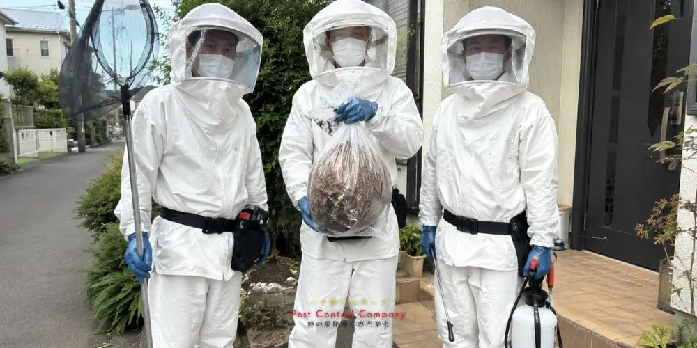 小平市の住宅前で防護服を着た作業員が撤去した蜂の巣を持っている様子